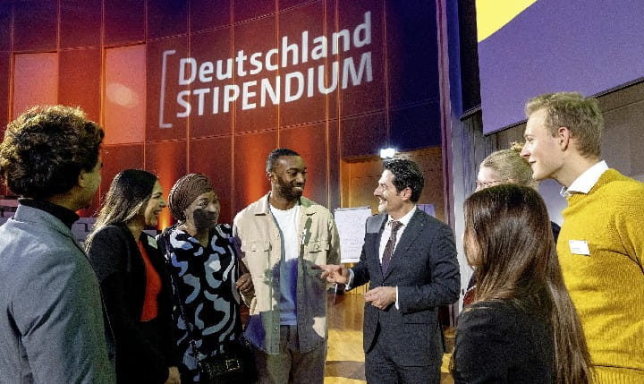 Stipendiaten und ein Redner unterhalten sich beim Deutschlandstipendium Event.