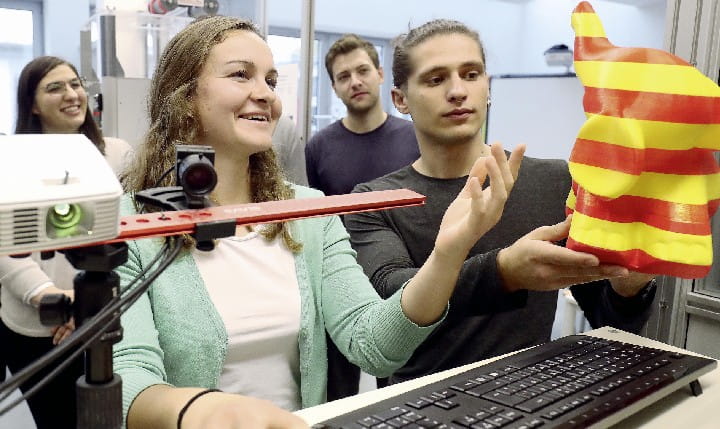 Mehrere Schüler, die in einer Werkstatt an einem 3d-gedruckten Modell arbeiten