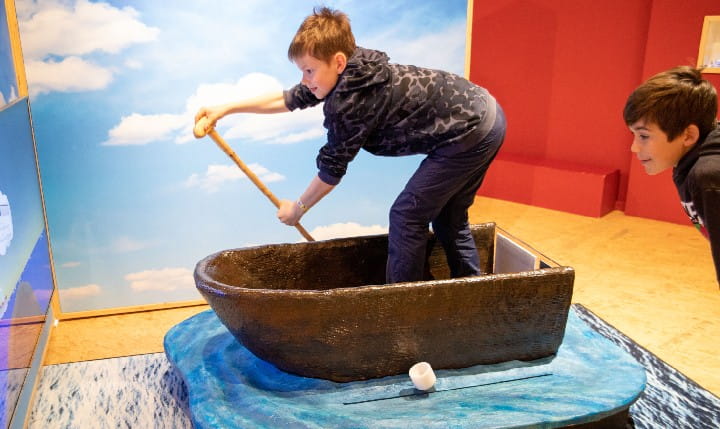 Zwei Kinder spielen an einem Ruderboot im Kindermuseum