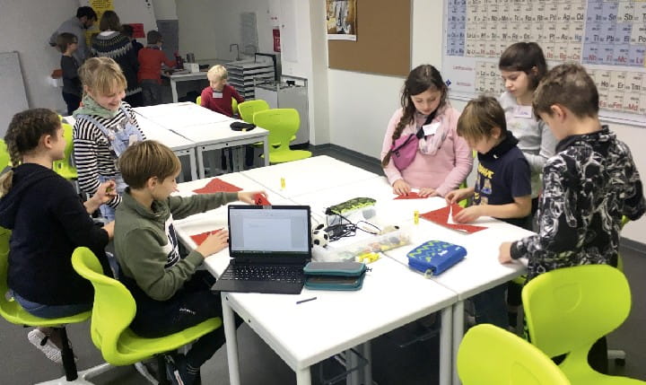 Einige Schüler arbeiten gemeinsam an einem Tisch in der Universitätsschule